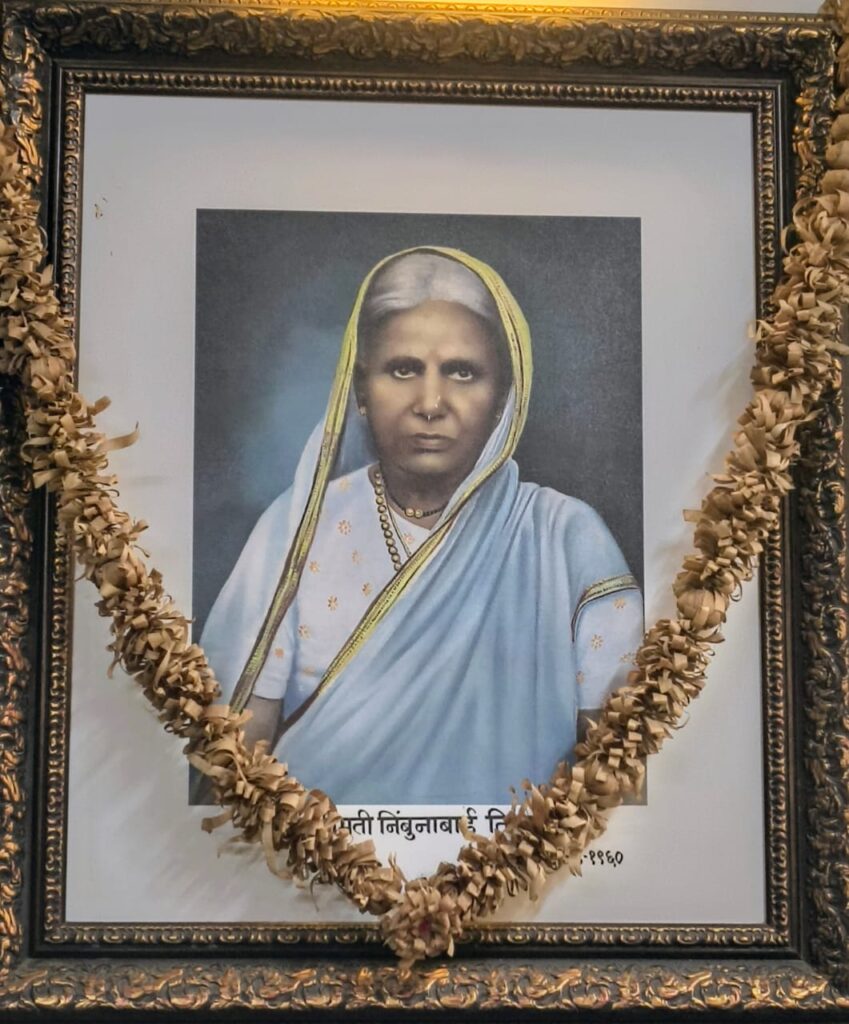 Framed portrait of an honorable elderly woman in traditional attire, garlanded as a mark of respect, symbolizing the legacy behind the hospital.